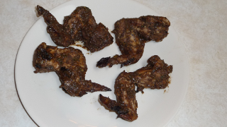Photograph of serving, showing four full wings, covered with spicy sauce.