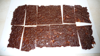Photograph of cooked sheet of jerky, sliced into individual serving pieces.